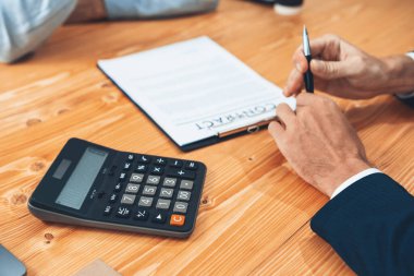 Finansal danışman ve müvekkil anlaşma imzalamadan önce konferans odasında belgeleri gözden geçiriyorlar. İşadamı, mali hesaplar ve ofisteki müşterilerin kredi faiz oranlarını analiz ediyor. Varlık