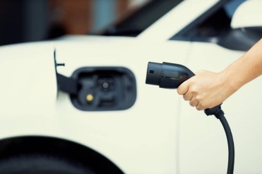 Gelişen elektrikli aracın bulanık arka planına sahip EV şarj prizi ile ev garajındaki elektrik şarj istasyonu temiz ve sürdürülebilir enerjiyle çalışan soket park yerine odaklan.