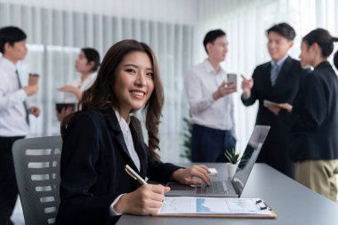 Focus portrait of female manger, businesswoman in the harmony meeting room with blurred of colleagues working together, analyzing financial paper report and dashboard data in background.
