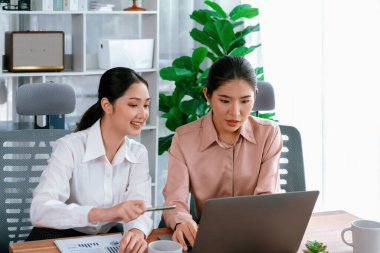 Modern ofis çalışma alanında iş birliği yapan iki genç ofis çalışanı, modern ofis çalışanı olarak profesyonelliklerini sergileyerek, dizüstü bilgisayarda tartışıyorlar ve birlikte çalışıyorlar. Coşkulu.