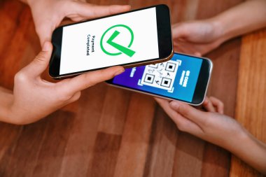 QR kodu parasız ödeme taraması için ekranda gösterilir. Kapalı eller, mobil uygulamadan elektronik işlem yoluyla para aktarmak için akıllı telefonu tutuyor. Hızlı ödeme için barkod teknolojisi. Coşkulu.