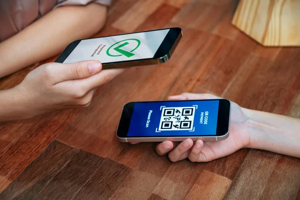 QR kodu parasız ödeme taraması için ekranda gösterilir. Kapalı eller, mobil uygulamadan elektronik işlem yoluyla para aktarmak için akıllı telefonu tutuyor. Hızlı ödeme için barkod teknolojisi. Coşkulu.