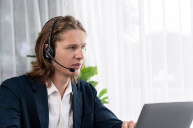 Erkek müşteri hizmetleri operatörü ya da telesales temsilcisi ofiste oturuyor, kulaklık takıyor ve müşteriyle satış desteği ya da kapanış konuşması yapıyor. Çağrı merkezi portresi. Varlık