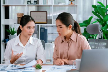 Modern ofis çalışma alanında iş birliği yapan iki genç ofis çalışanı, modern ofis çalışanı olarak profesyonelliklerini sergileyerek, dizüstü bilgisayarda tartışıyorlar ve birlikte çalışıyorlar. Coşkulu.