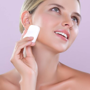 Yüz makyajı konsepti için pudra pudrası uygulayan güzel bir model. Kusursuz kozmetik ciltli kadın portresi yüzüne pembe izole edilmiş bir fondöten sürdü..