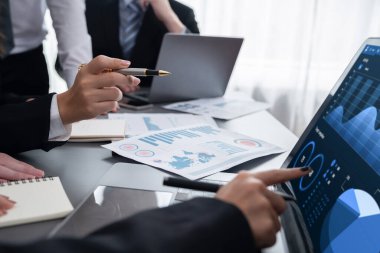 İş adamlarıyla toplantı masasına yakın çekim. İş pazarlama stratejisini analiz ediyorlar. Elleri dizüstü bilgisayarla çalışıyorlar..