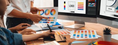Grafik tasarımcısı, modern dijital stüdyo işyerinde profesyonel grafik ekibiyle benzersiz bir tasarım yaparken bilgisayar dizüstü bilgisayar ve grafik çizim kalemi üzerinde çalışır. Panorama çekimi. İnceleyin