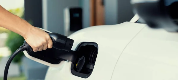 stock image Progressive concept of hand insert an emission-free power connector to the battery of electric vehicle at home. Electric vehicle charging via cable from charging station to EV car battery