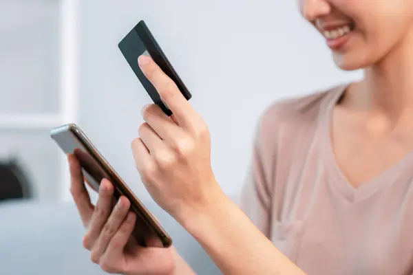 stock image Contented young woman eagerly makes an online purchase using her smartphone. E-commerce business, online purchasing.