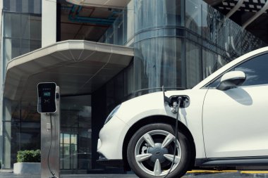 Şehrin yerleşim bölgesindeki sürdürülebilir temiz enerjiyle şarj edilen şarj istasyonunda ilerleyen elektrikli araç şarj bataryası. Çevre dostu araç kavramı.