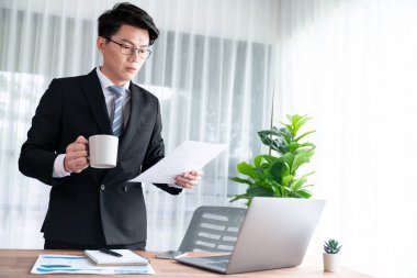 Ofis masasında dizüstü bilgisayarda çalışan bir iş adamı. Akıllı yönetici finansal iş verilerini araştırıyor ya da bilgisayarla stratejik iş pazarlaması planlıyor. Sevinçli.