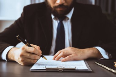 İş adamı sözleşme kağıtlarını ya da iş hukukunu güven ve profesyonellikle imzalar. Resmi iş anlaşması için şirket toplantısında el ele tutuşmak. Eşitlik