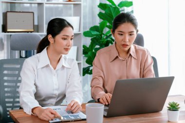 Modern ofis çalışma alanında iş birliği yapan iki genç ofis çalışanı, modern ofis çalışanı olarak profesyonelliklerini sergileyerek, dizüstü bilgisayarda tartışıyorlar ve birlikte çalışıyorlar. Coşkulu.