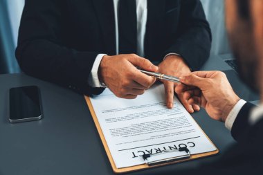 İş anlaşması yapılırken iki işadamı masanın karşısında oturuyor. Şirket avukatı, sözleşmeyi imzalaması için müvekkiline ya da ortağına kalem veriyor ve anlaşmayı imzayla imzalıyor. Coşkulu