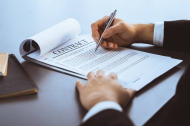 İş adamı sözleşme kağıtlarını ya da iş hukukunu güven ve profesyonellikle imzalar. Resmi iş anlaşması için şirket toplantısında el ele tutuşmak. Eşitlik