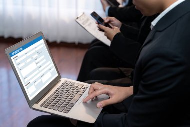 İş başvurusu yapan kişi diğer adaylarla iş görüşmesi için bekleme odasında otururken şirket şirketinde dizüstü bilgisayarla iş başvurusunda bulunuyor. Modern iş arayanlar ve iş arayanlar. Önde.