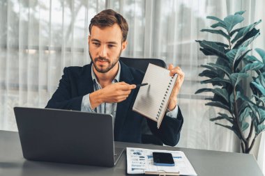 İşadamı ofis masasından sanal ofis toplantısı düzenliyor ve uzaktan çalışanlarla uzak iletişim kurmak için dizüstü bilgisayardaki Webinar uygulamasını kullanarak çevrimiçi video konferansını tartışıyor. Varlık
