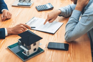 Müşteri ve emlakçı kredi sözleşmesini gözden geçirir, terimleri, faiz oranlarını ve mülkiyet haklarını tartışır. Yasal belgeleri analiz et ve karar vermeden önce anlaşmayı iyice oku. Varlık