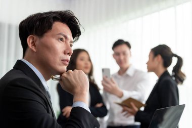 Portrait of focus young successful confident male manager, executive wearing business wear in harmony office arm crossed with blurred meeting background of colleagues, office worker.