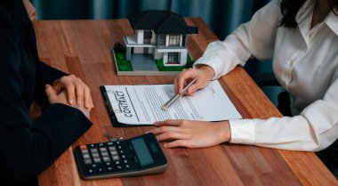 Temsilciyle ev kredisi sözleşmesini gözden geçiriyorum. Mali belgeleri ve vergi oranlarını, mülkiyet sahibi olmak için hesap makinesiyle analiz ediyorum. Yeni ev alımı ve finansman için anahtar imza. Coşkulu.