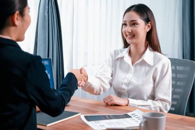 Asyalı kadın aday ve iş ofisinde tokalaşma ile mülakatçı arasında başarılı bir iş görüşmesi. Pozitif nitelik ve pozisyon için başvuru. Coşkulu.