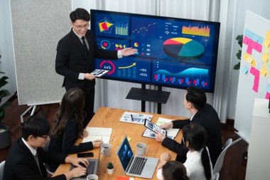 Confidence and asian businessman give presentation on financial analyzed by business intelligence in dashboard report to other people in board room meeting to promote harmony in workplace.