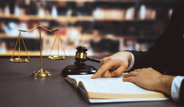 Avukatı ya da avukatı dava ya da dava açmaya hazırlanıyor, hukuk fakültesi konsepti için kütüphanedeki masasında hukuk kitabı okuyor ya da okuyor, hukuki sembollerle süslenmiş. Eşitlik