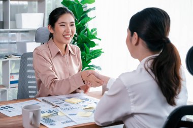 İki Asyalı iş kadını, iş yeri konseptinde takım çalışması ve dürüstlüğün önemi olarak, gösterge paneli veri kağıtlarının yığınlarını başarıyla analiz ettikten sonra modern ofiste el sıkışıyor. Coşkulu.