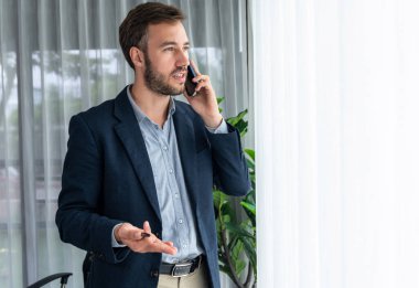 Çalışkan iş adamı, modern ofiste güvenilir bir şekilde müşteriye ikna edici satış çağrıları yapıyor. Ofis çalışanı telefonda konuşuyor ve iş arkadaşlarıyla iş görüşmesi yapıyor. Varlık