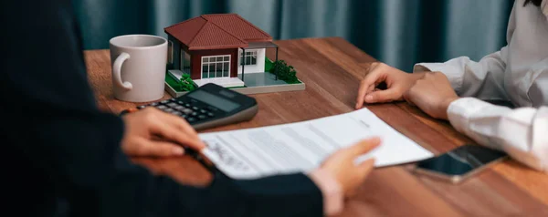 Reviewing house loan contract with agent. Analyzing financial documents and tax rates with calculator for ownership of property. Key signature for new home purchase and financing. Enthusiastic