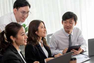 Harmony in office concept as business people analyzing dashboard paper together in workplace. Young colleagues give ideas at manager desk for discussion or strategy planning about project.