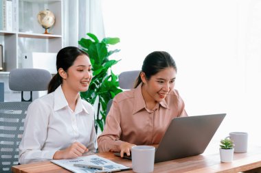 Modern ofis çalışma alanında iş birliği yapan iki genç ofis çalışanı, modern ofis çalışanı olarak profesyonelliklerini sergileyerek, dizüstü bilgisayarda tartışıyorlar ve birlikte çalışıyorlar. Coşkulu.