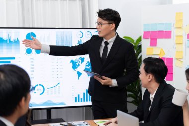 Confidence and asian businessman give presentation on financial analyzed by business intelligence in dashboard report to other people in board room meeting to promote harmony in workplace.