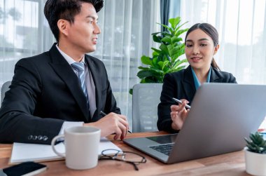 İki Asyalı ofis çalışanı şirket işyerinde birlikte çalışıp tartışıyorlar. Gülümseyen ve planlayan iş arkadaşları, kurumsal çalışma alanındaki dostane çalışma ortamında çalışırlar. Sevinçli.