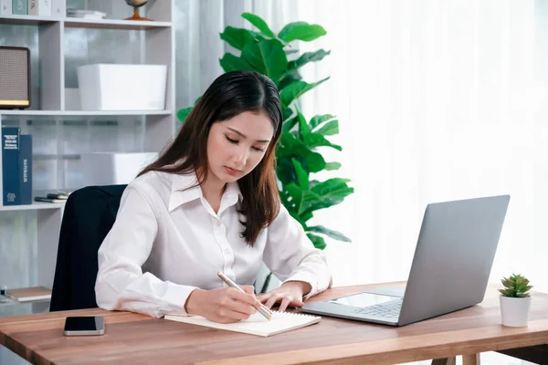 ラップトップを使用してノートパソコンを使用して仕事やメモを書く現代のオフィスデスクで若いアジアの熱狂的な実業家 勤勉で魅力的なオフィスの女性は彼女のオフィスワークスペースでコンピュータノートブックに取り組んで — ストック写真
