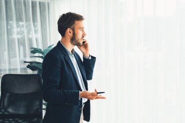 Çalışkan iş adamı, modern ofiste güvenilir bir şekilde müşteriye ikna edici satış çağrıları yapıyor. Ofis çalışanı telefonda konuşuyor ve iş arkadaşlarıyla iş görüşmesi yapıyor. Varlık