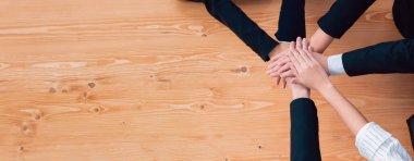 Top view partial hands wearing formal suit joining stack and form circle as symbol of team building, unity and harmony in office workplace. Successful business team of synergy holding hand together.