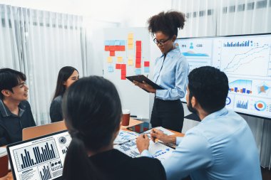 Genç Afrikalı iş kadını modern toplantıda TV ekranında veri analizi paneli sunuyor. Bir grup iş adamıyla konferans odasında iş sunumu. Uyum