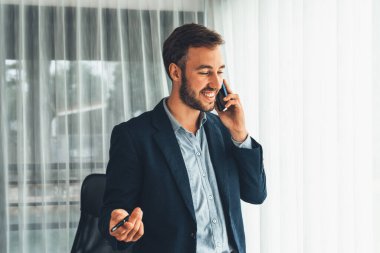 Çalışkan iş adamı, modern ofiste güvenilir bir şekilde müşteriye ikna edici satış çağrıları yapıyor. Ofis çalışanı telefonda konuşuyor ve iş arkadaşlarıyla iş görüşmesi yapıyor. Varlık