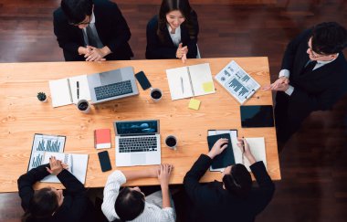 Top view manager or office worker give presentation in harmony conference room to business colleague, BI data dashboard on screen and pile of financial analyzed data reports on meeting table.