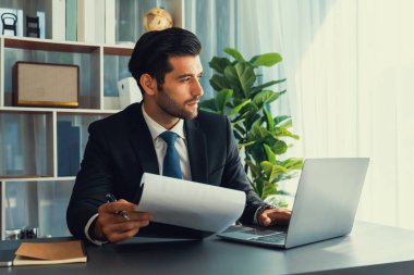 Modern ofis masasındaki modern profesyonel iş adamı çalışmak ve notlar yazmak için dizüstü bilgisayar kullanıyor. Ofisinde bilgisayar defteri üzerinde çalışan çalışkan bir ofis çalışanı. coşkulu