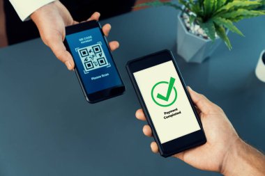 Parasız ödeme taraması için QR kodu ekranda görüntülendi. Kapalı eller, mobil uygulamadan elektronik işlem yoluyla para aktarmak için akıllı telefonu tutuyor. Hızlı ödeme için barkod teknolojisi. Coşkulu