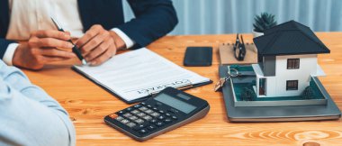 Müşteri ve emlakçı kredi sözleşmesini gözden geçirir, terimleri, faiz oranlarını ve mülkiyet haklarını tartışır. Yasal belgeleri analiz et ve karar vermeden önce anlaşmayı iyice oku. Varlık