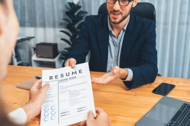 Aday özgeçmişini ya da CV 'yi şirket toplantı odasında mülakata veriyor. İş başvurusunda bulunan kişi, iş tecrübesini ve niteliğini İK müdürüne göstermemiş. Varlık
