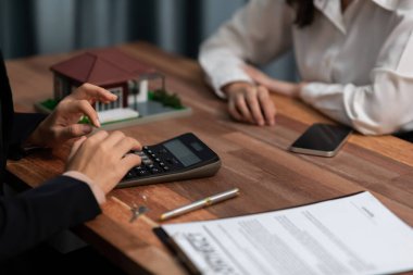 Temsilciyle ev kredisi sözleşmesini gözden geçiriyorum. Mali belgeleri ve vergi oranlarını, mülkiyet sahibi olmak için hesap makinesiyle analiz ediyorum. Yeni ev alımı ve finansman için anahtar imza. Coşkulu.