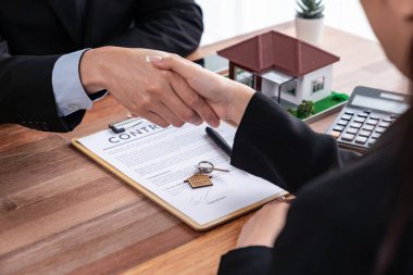 Ev kredisi anlaşması başarılı bir şekilde tokalaşmayla sonuçlandı. Alıcılar ve emlakçılar ev sahipliği anlaşmasını başarı ve memnuniyet duygusuyla kutluyorlar. Sevinçli.