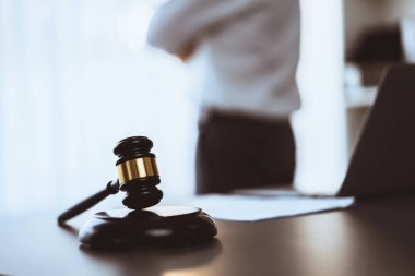 Hukuk bürosunun masasında yasal evraklarla çalışan avukatın bulanık arkaplanına odaklanın. Kanun yapıcı ve avukatın adil ve adil yargılaması için meşru çekiç. Eşitlik