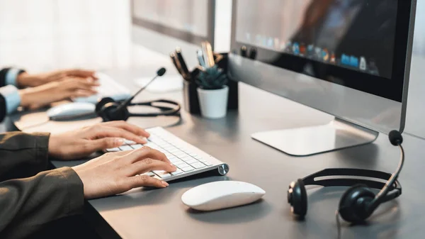 stock image Panorama focus hand holding headset on call center workspace desk with blur background of operator team or telesales representative engaging in providing client with customer support service. Prodigy