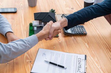 Ev kredisi anlaşmasını el sıkışma, alıcı ve emlakçı ile sonuçlandırmak mülkiyet sahipliğinin başarısını memnuniyet duygusuyla kutluyor. Yeni ev sahibi brokerla el sıkışıyor. Varlık