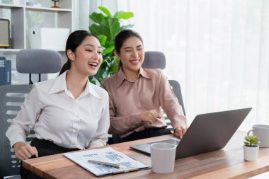 Modern ofis çalışma alanında iş birliği yapan iki genç ofis çalışanı, modern ofis çalışanı olarak profesyonelliklerini sergileyerek, dizüstü bilgisayarda tartışıyorlar ve birlikte çalışıyorlar. Coşkulu.